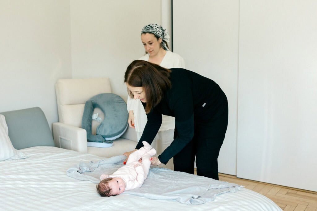 Postpartum Doula teaching mom how to swaddle newborn