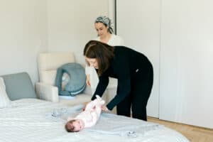Postpartum Doula teaching mom how to swaddle newborn